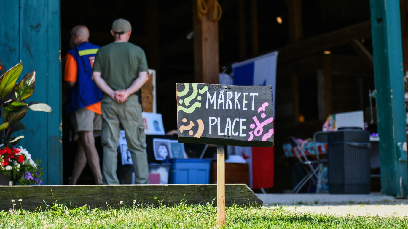 A wooden sign reading Market Place in front of the Wellington County Museum and Archive's Heritage Barn.