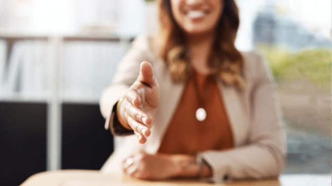 Shot an unrecognizable businesswoman reaching out for a handshake in her office