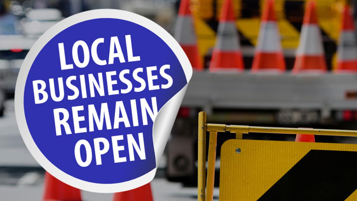 Text Reads: Local Businesses Remain Open sticker over a construction site. 