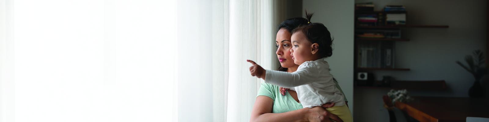 Woman holding her child while looking out a window